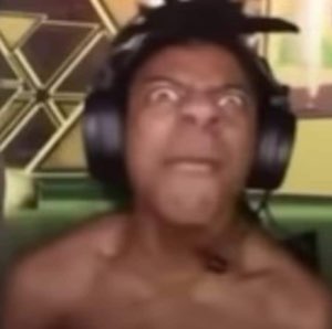 Blurry shirtless man in headphones scowling intensely into his webcam