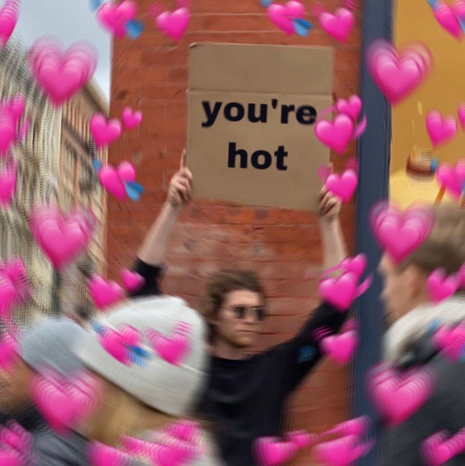Person on a street holding up a cardboard sign that says 'you're hot', buried in heart emojis