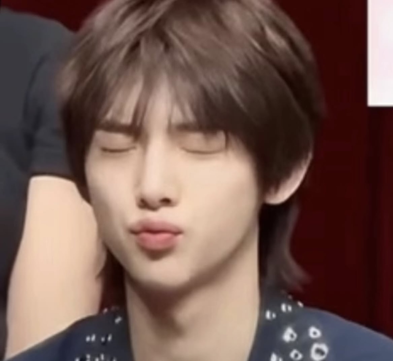 Young man with closed eyes puckering his lips in an exaggerated pout