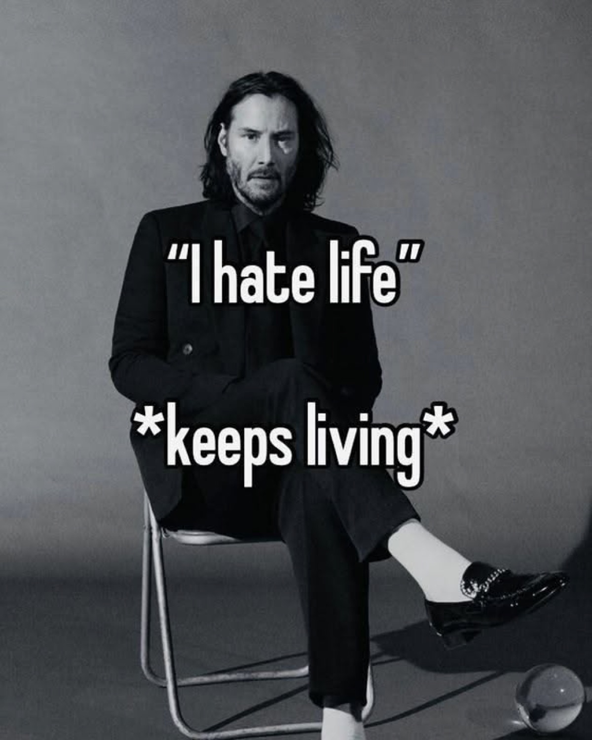 Keanu Reeves sitting slumped on a chair under '"I hate life" *keeps living*'