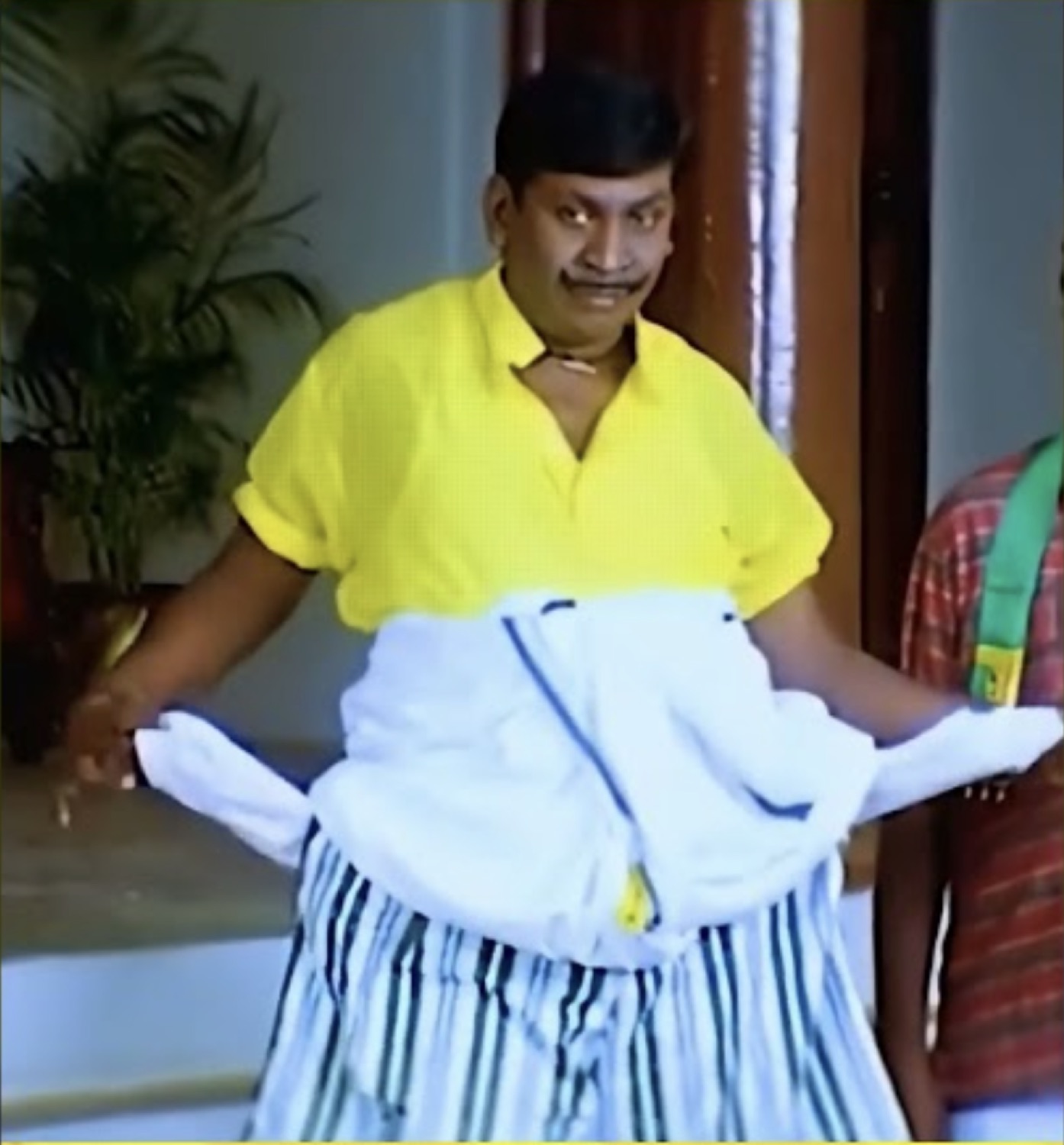 Vadivelu holding a shirt with a sheepish grin