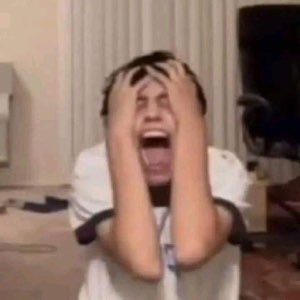 Guy gripping his head and screaming in a messy room