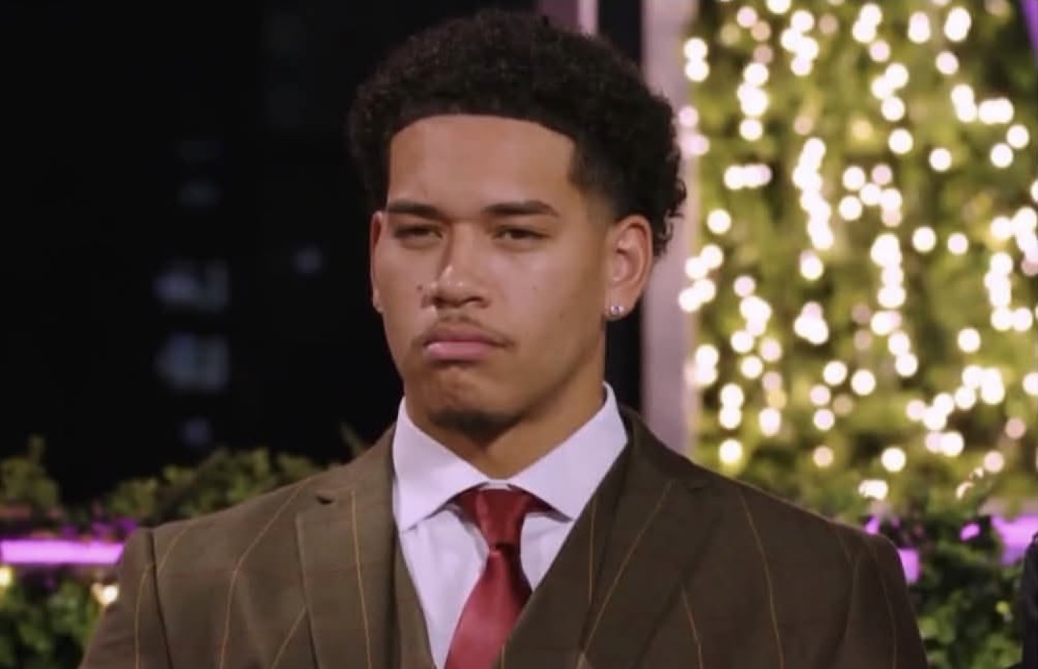 Love Island USA's Corbin in a suit with a skeptical frown