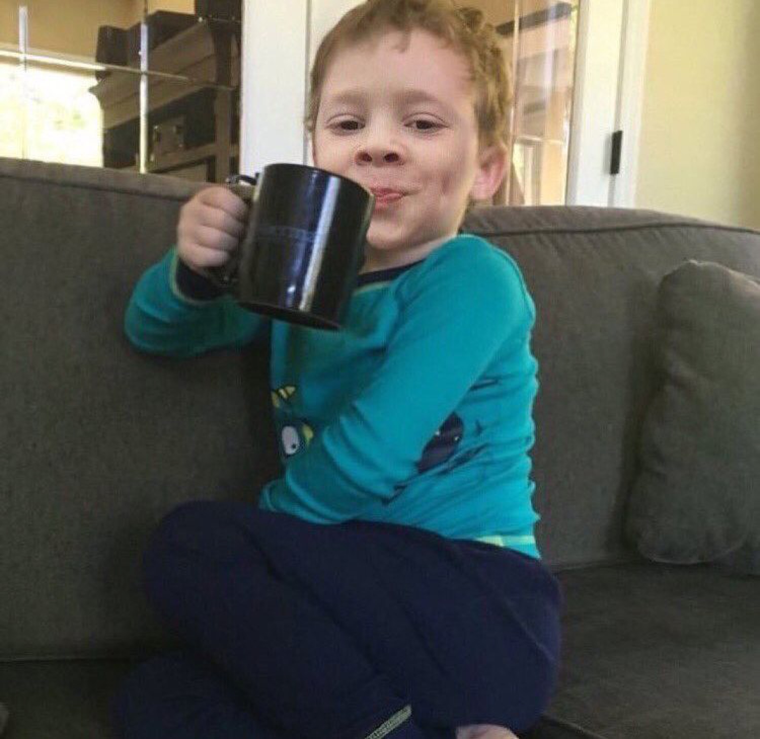 Little boy in pajamas sipping from a big mug with a smug, satisfied look