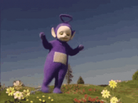 Tinky Winky from the Teletubbies dancing in a field of flowers
