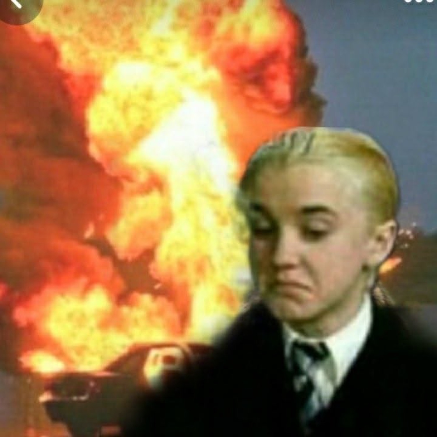 Draco Malfoy grimacing in disgust in front of a fiery explosion