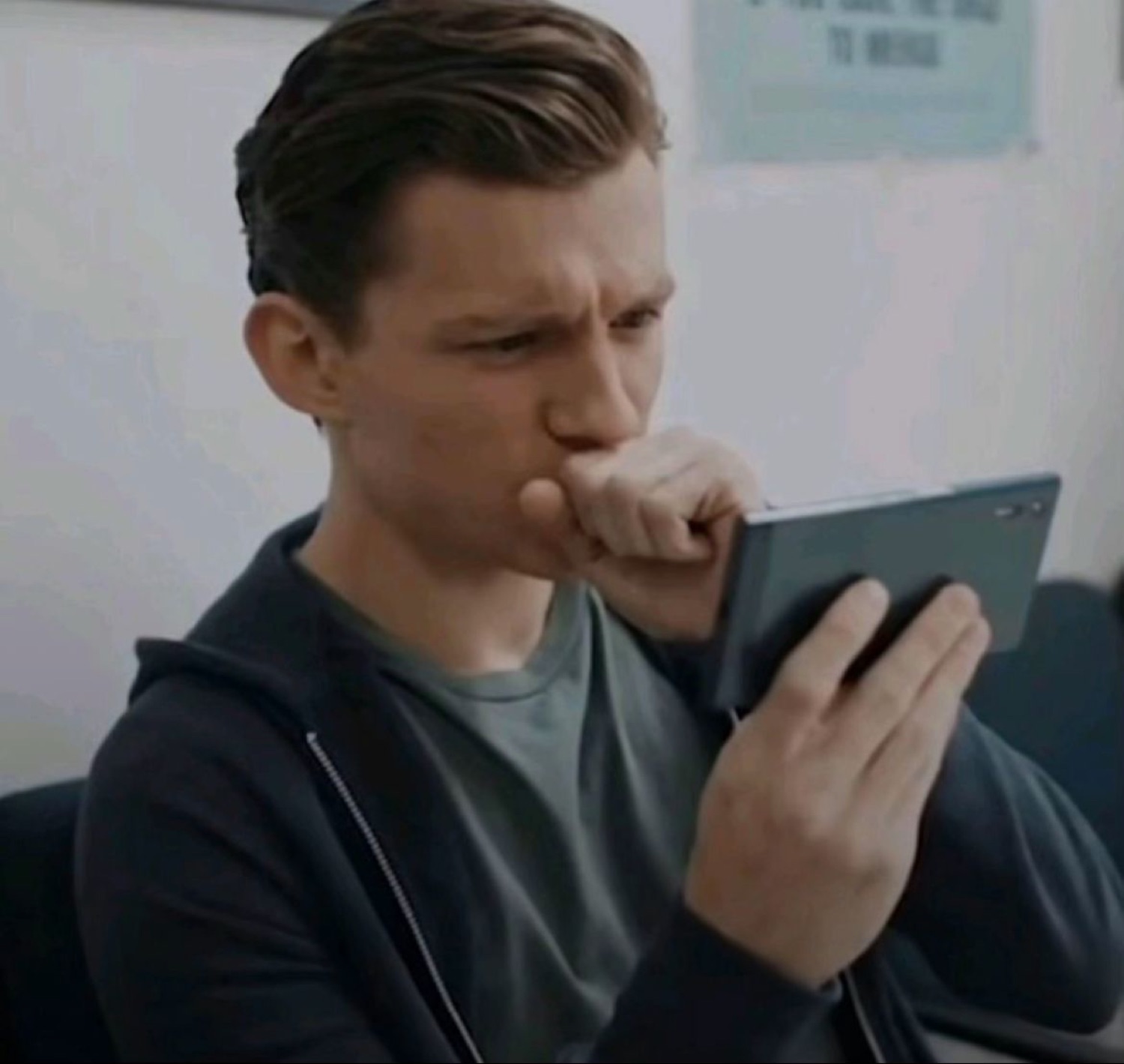 Tom Holland staring at his phone with a hand over his mouth