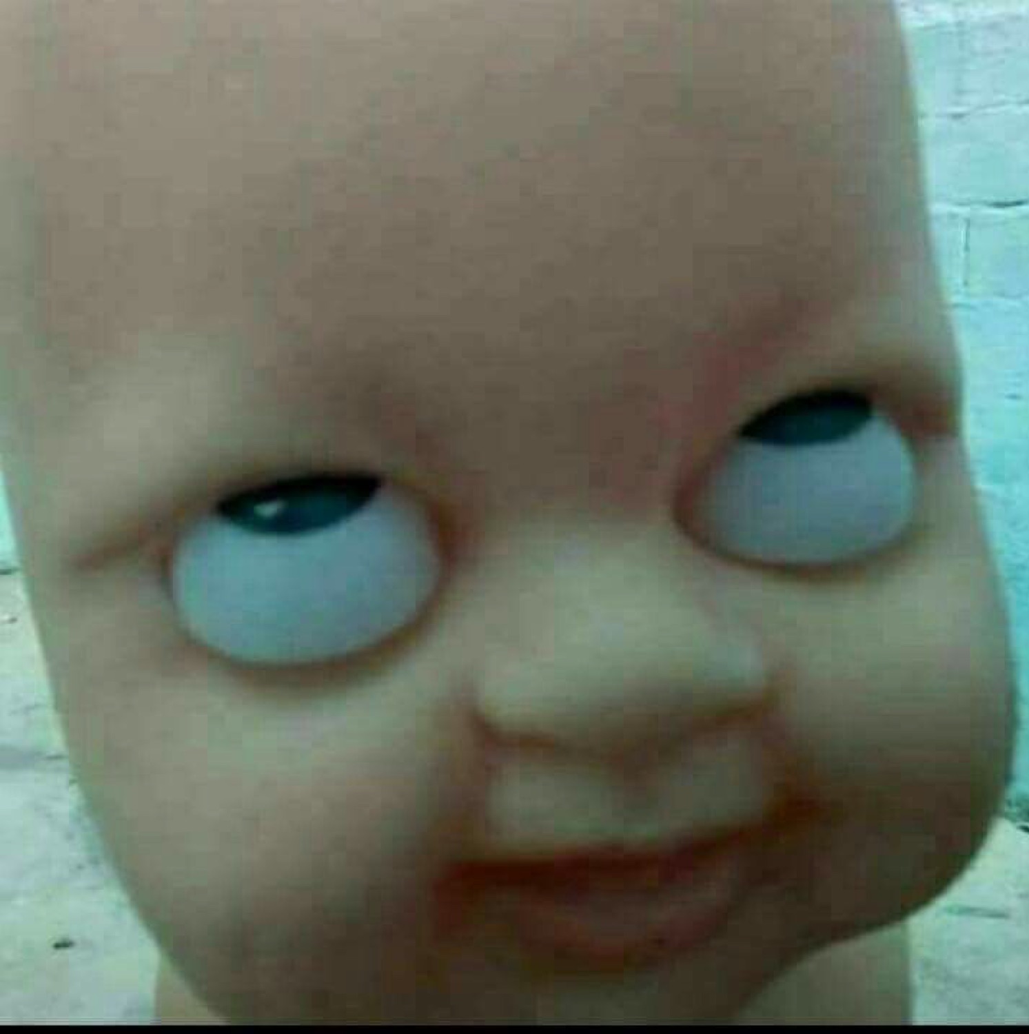 Creepy baby doll face with wonky, crossed eyes and a tiny smirk