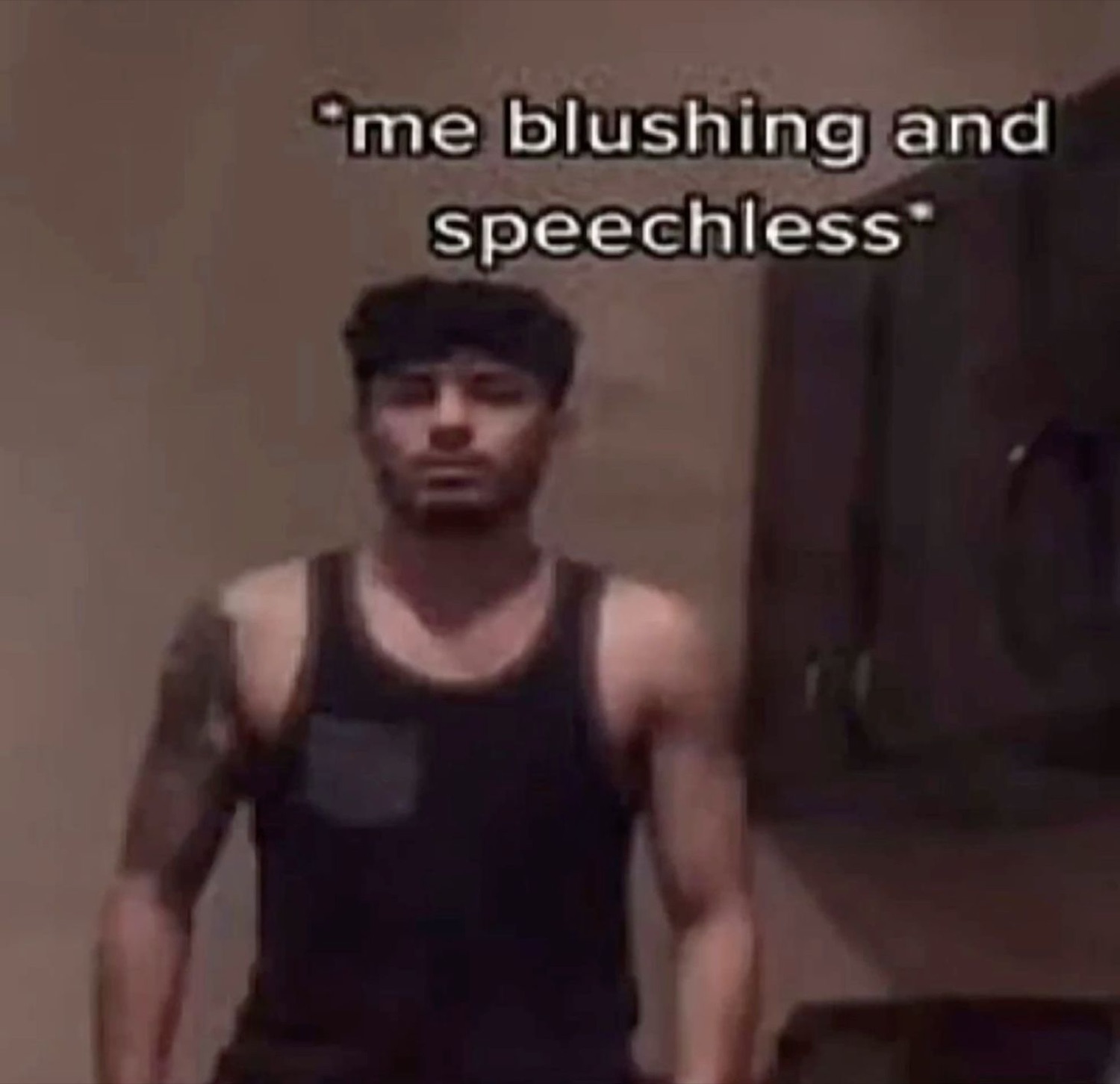 Man in a tank top standing deadpan captioned '*me blushing and speechless*'