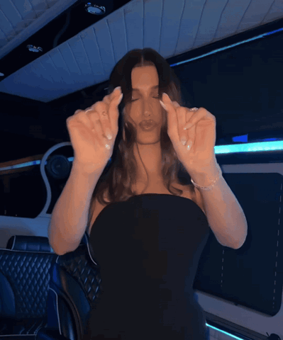 Woman in a black strapless top making a heart shape with her hands