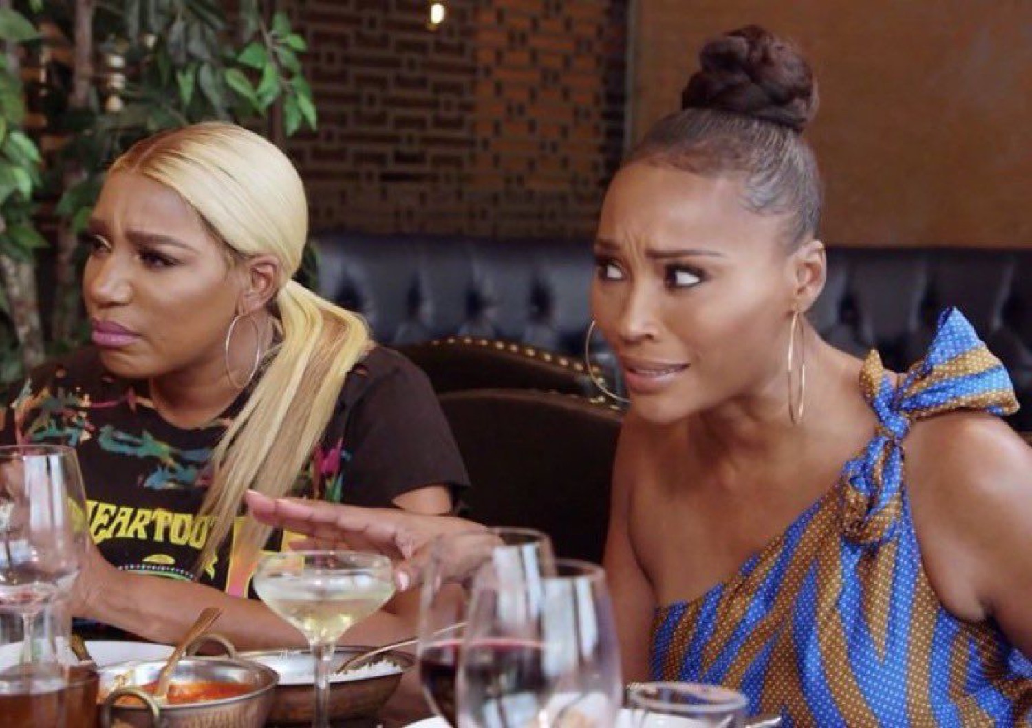 Two women at a restaurant table shooting matching disgusted, skeptical side-eyes