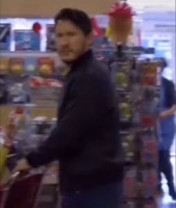 Man in a store turning to glance back over his shoulder with a wary side-eye
