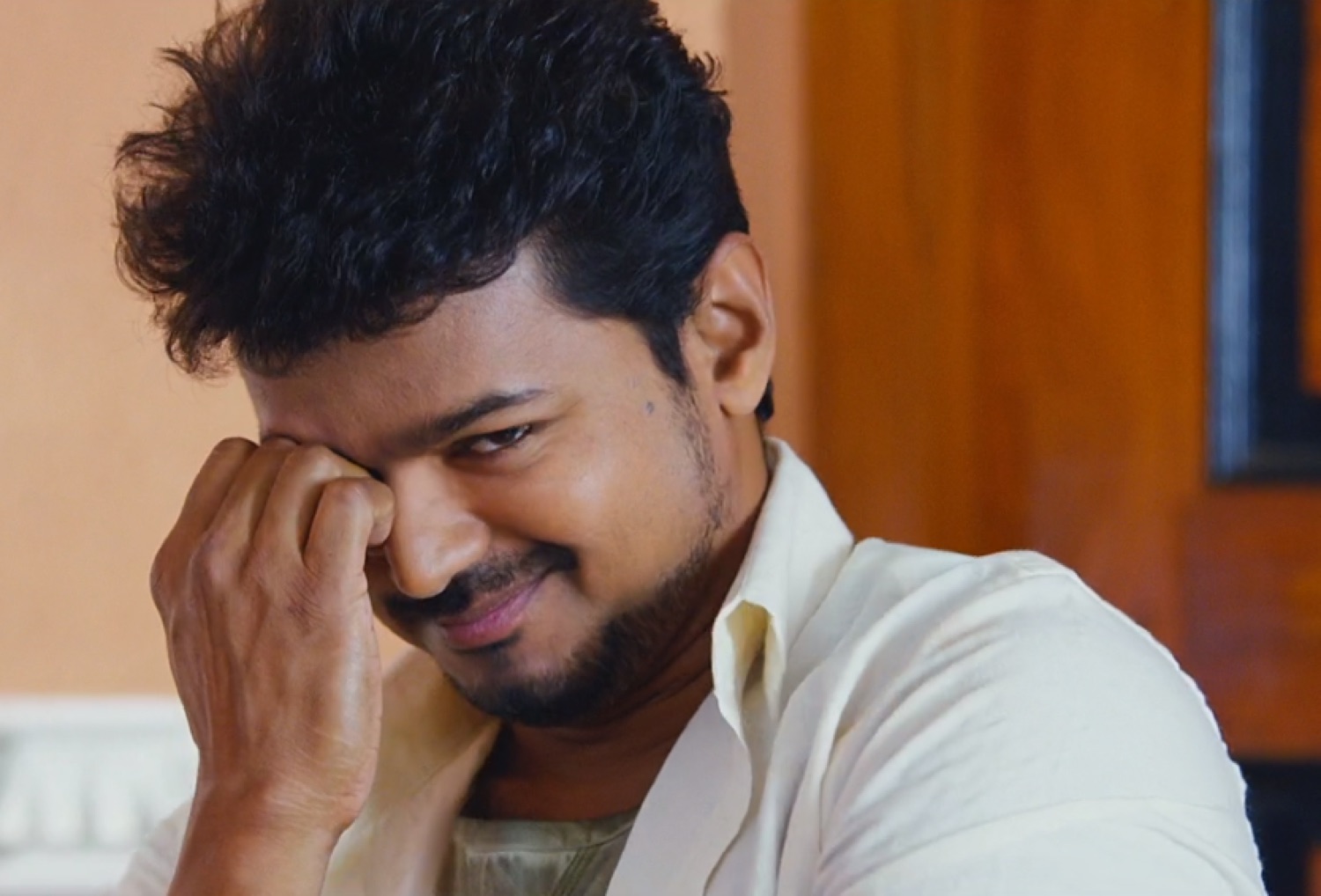 Vijay laughing shyly with his hand at his face