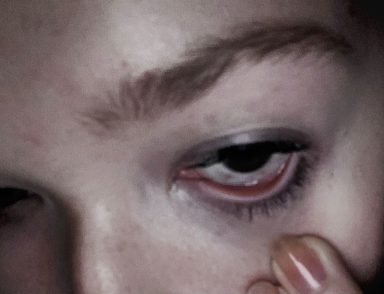 Extreme close-up of a teary eye staring blankly into the camera