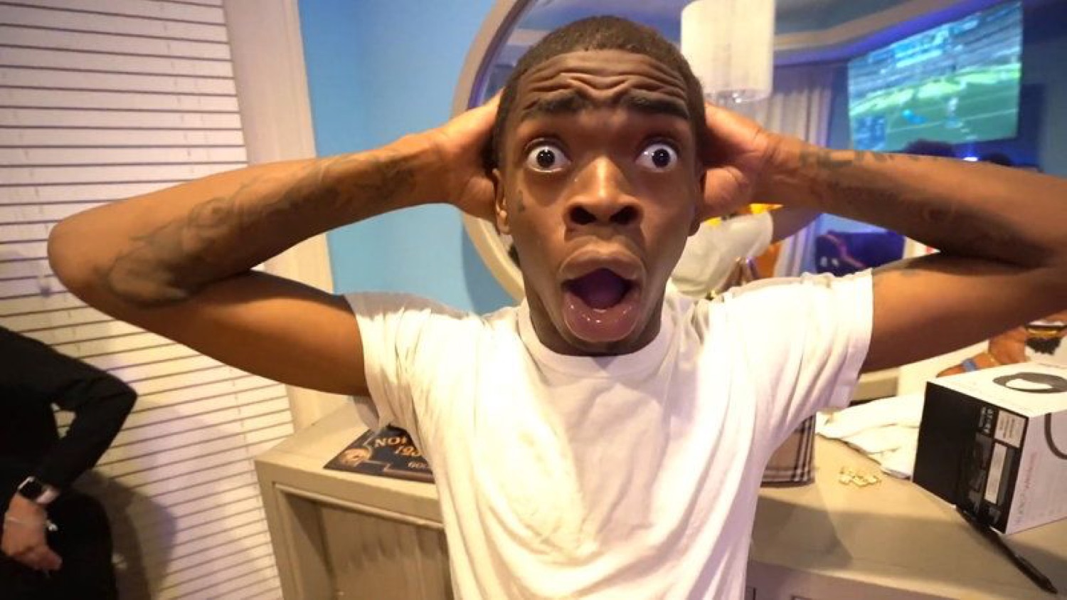 Guy in white tee grabbing his head with wide eyes and open mouth in total shock