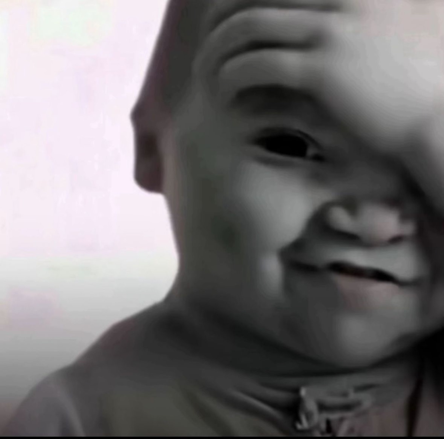 Chubby baby grinning sideways in a grainy black-and-white close-up