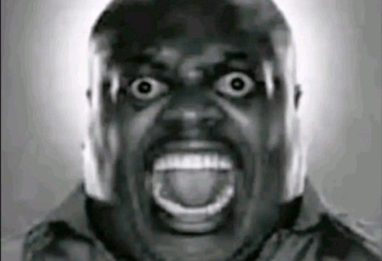 Grainy black-and-white shot of a man screaming with bulging wide eyes