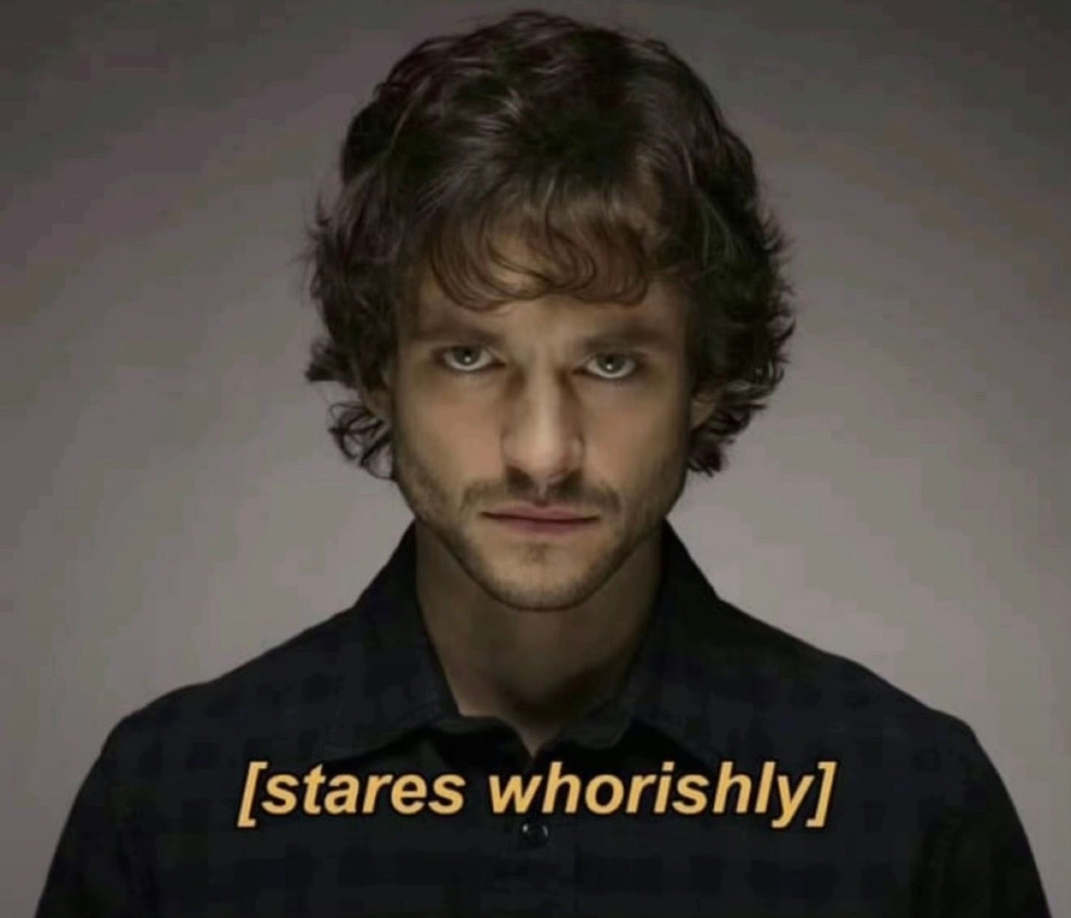 Curly-haired man staring intensely into the camera, captioned '[stares whorishly]'
