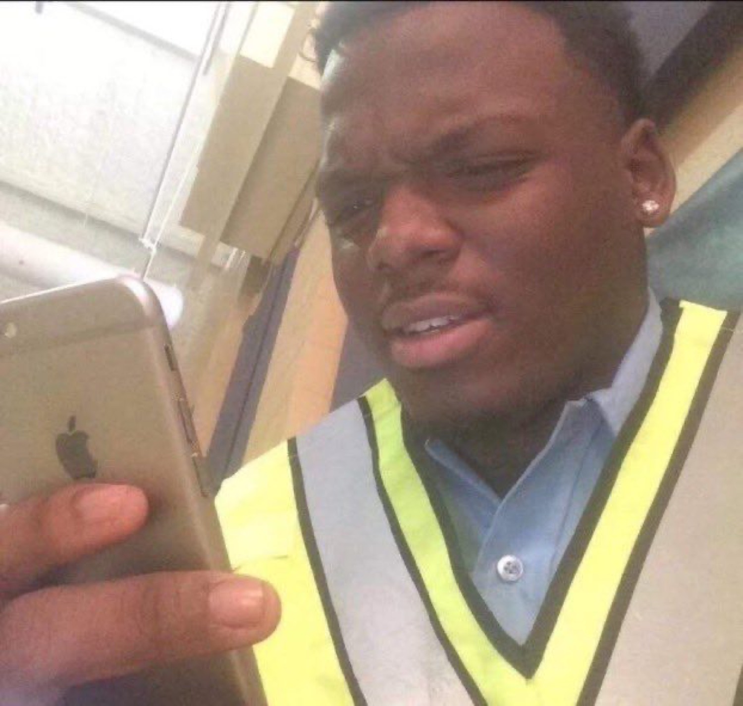 Man in a hi-vis vest squinting at his phone with a disgusted, unimpressed grimace