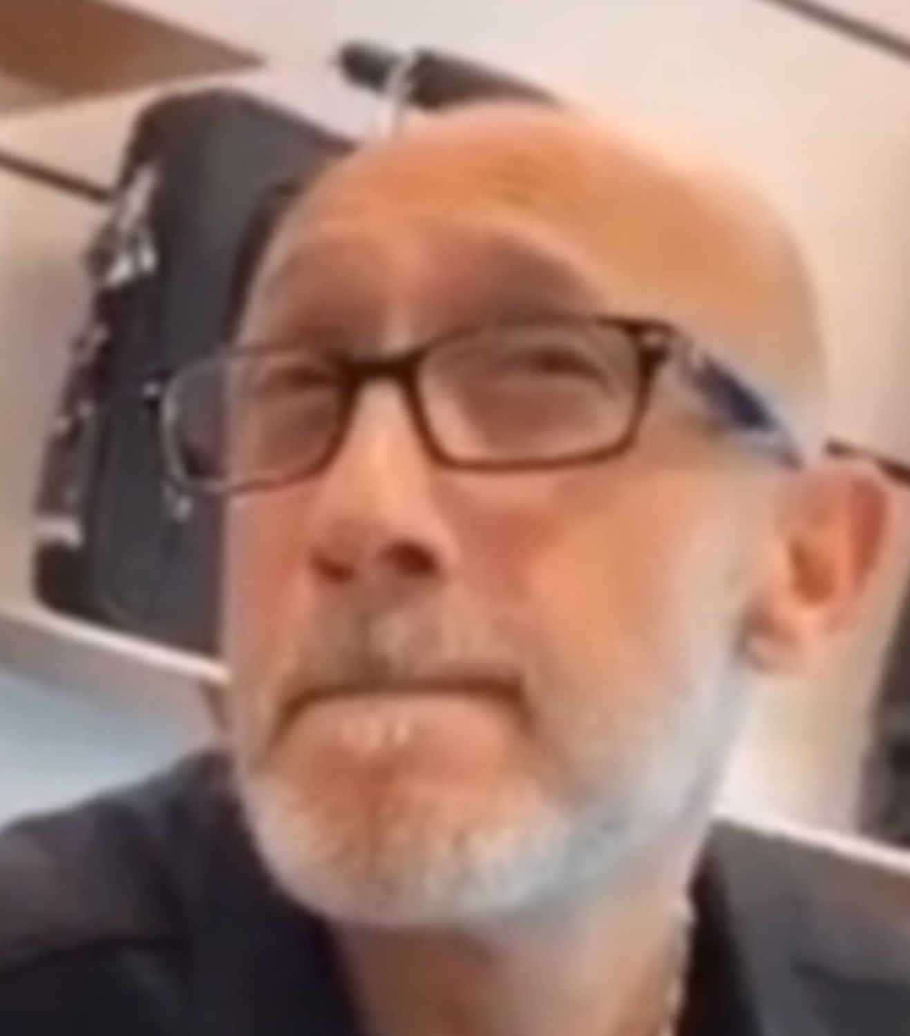 Bald man in glasses with a blank, unsure stare