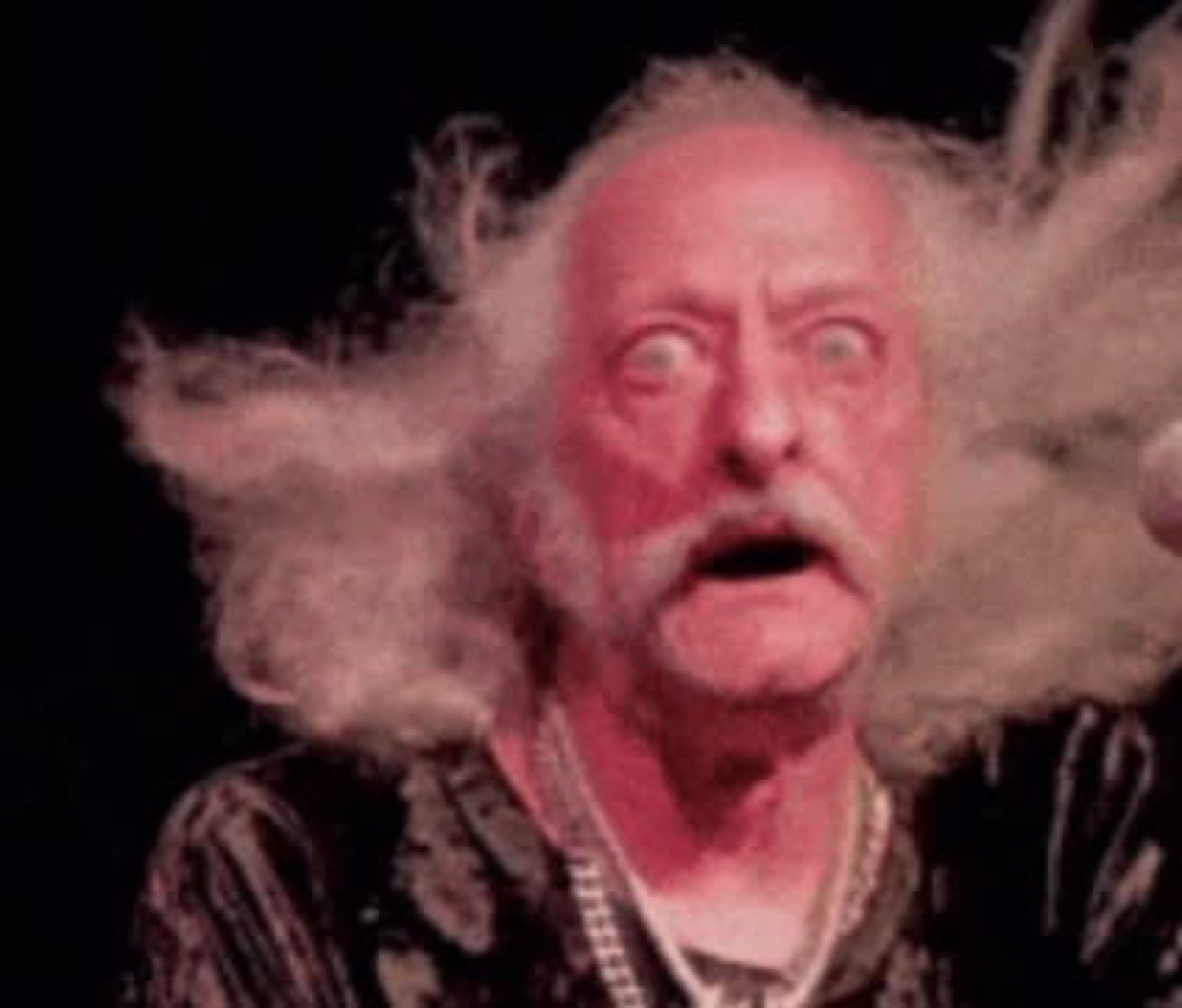 Old man with wild white hair and a red-lit, horrified open-mouthed stare