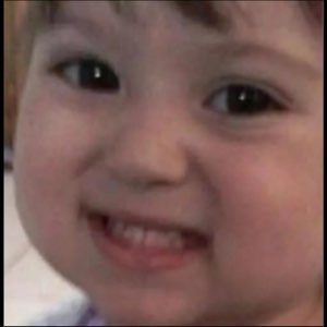 Close-up of a grinning toddler with a mischievous little smile