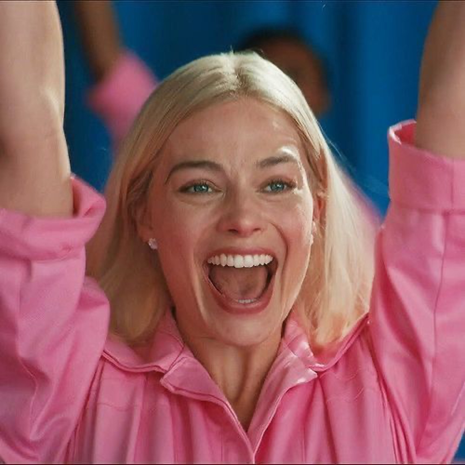 Margot Robbie as Barbie throwing her arms up and cheering with a huge grin