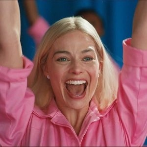 Margot Robbie as Barbie throwing her arms up and cheering with a huge grin
