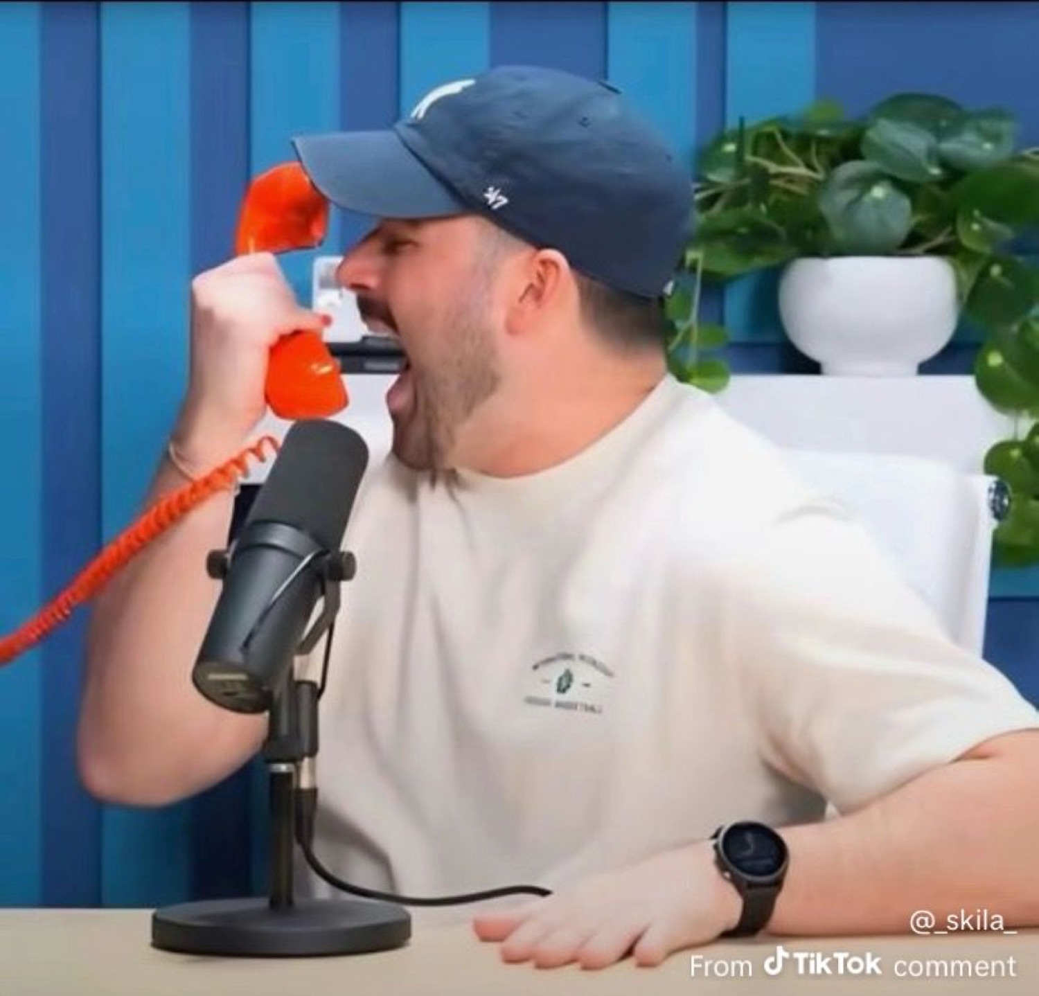 Podcast guy yelling into an orange corded phone at full volume