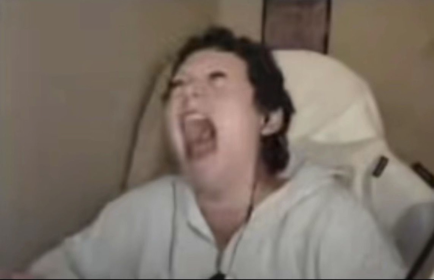 Person in a gaming chair throwing their head back, shrieking with laughter
