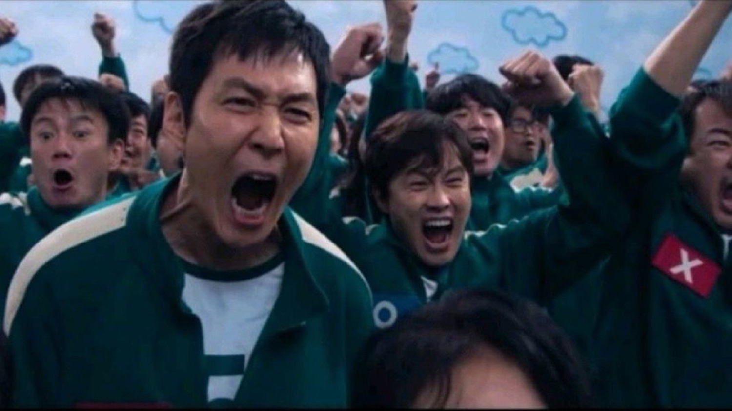 Squid Game players in green tracksuits roaring and pumping fists in celebration
