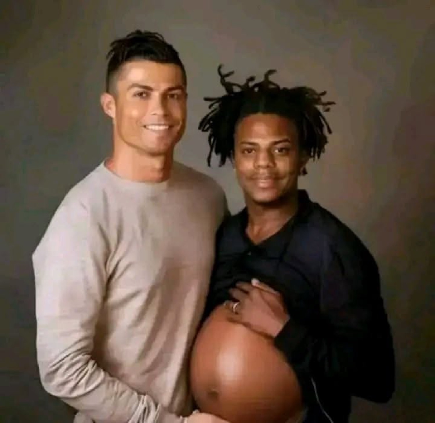 Cristiano Ronaldo smiling next to a man posing as if pregnant in a maternity-style photo