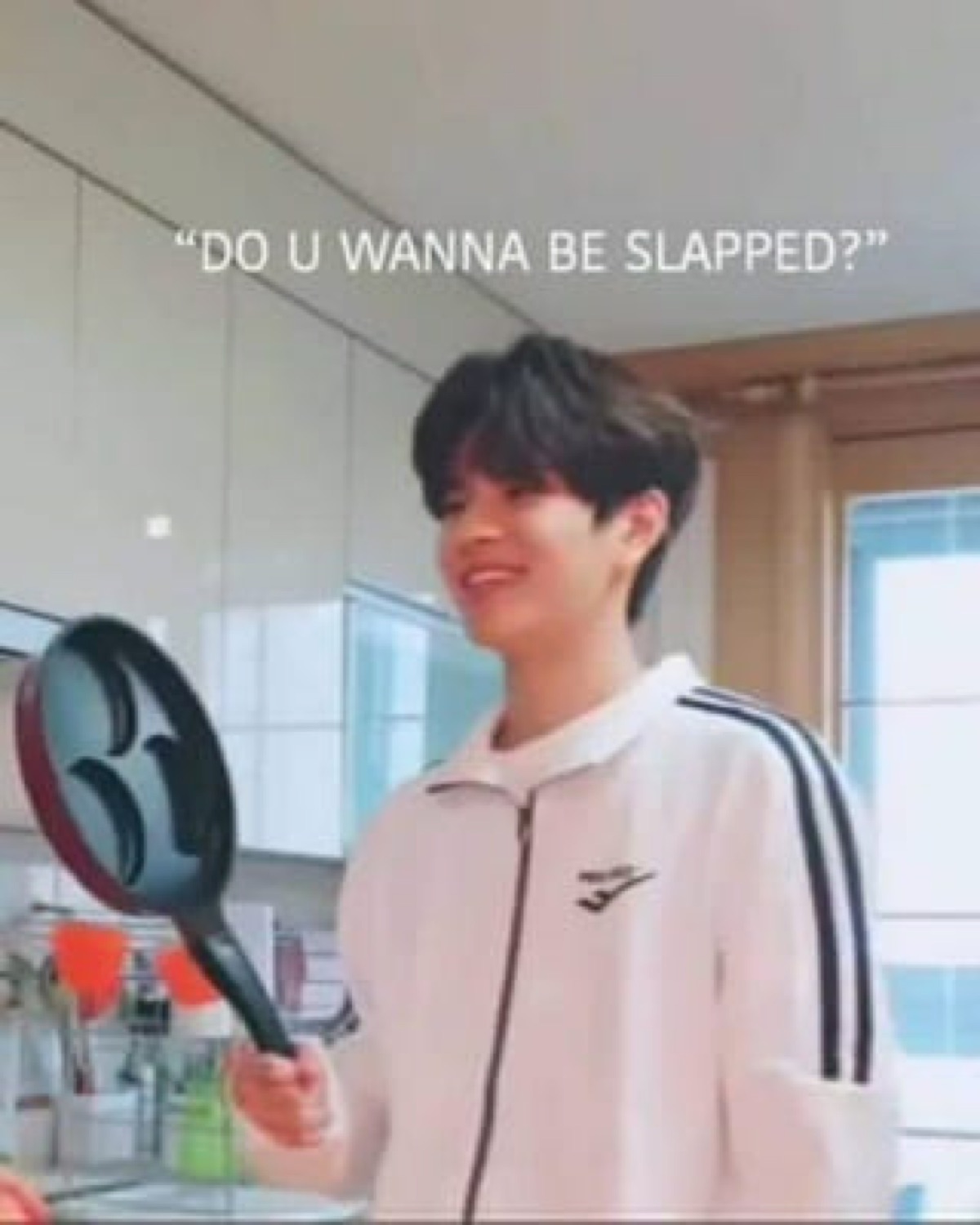 Guy in a kitchen raising a frying pan, captioned 'DO U WANNA BE SLAPPED?'
