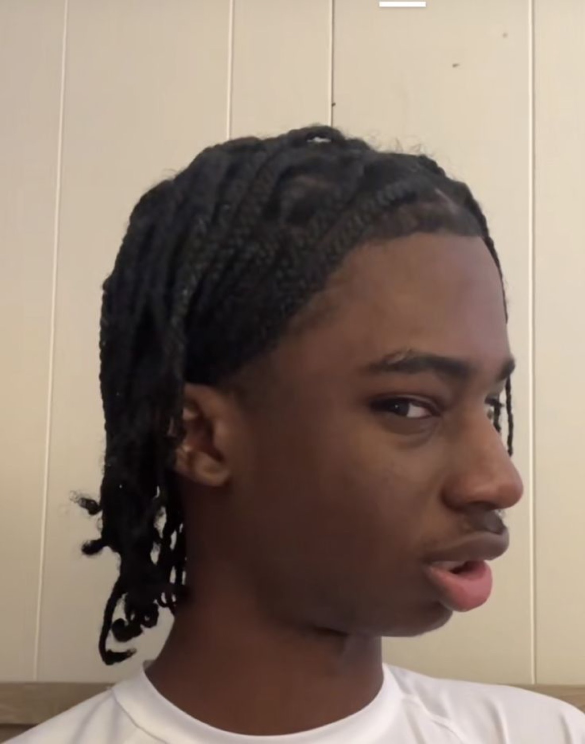 Teen with braids glancing sideways with a skeptical, unbothered look