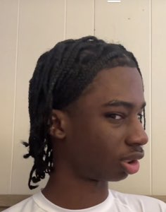 Teen with braids glancing sideways with a skeptical, unbothered look