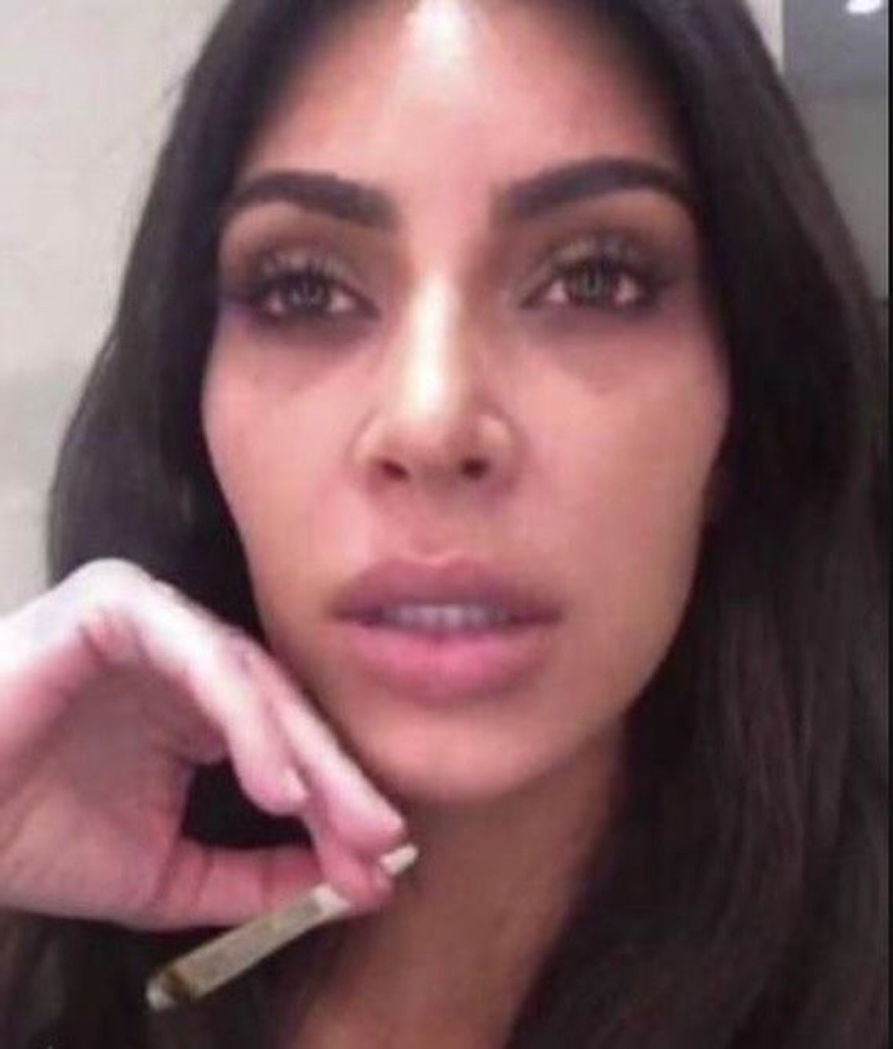 Woman holding a rolled cigarette to her lips with a totally blank, glazed stare