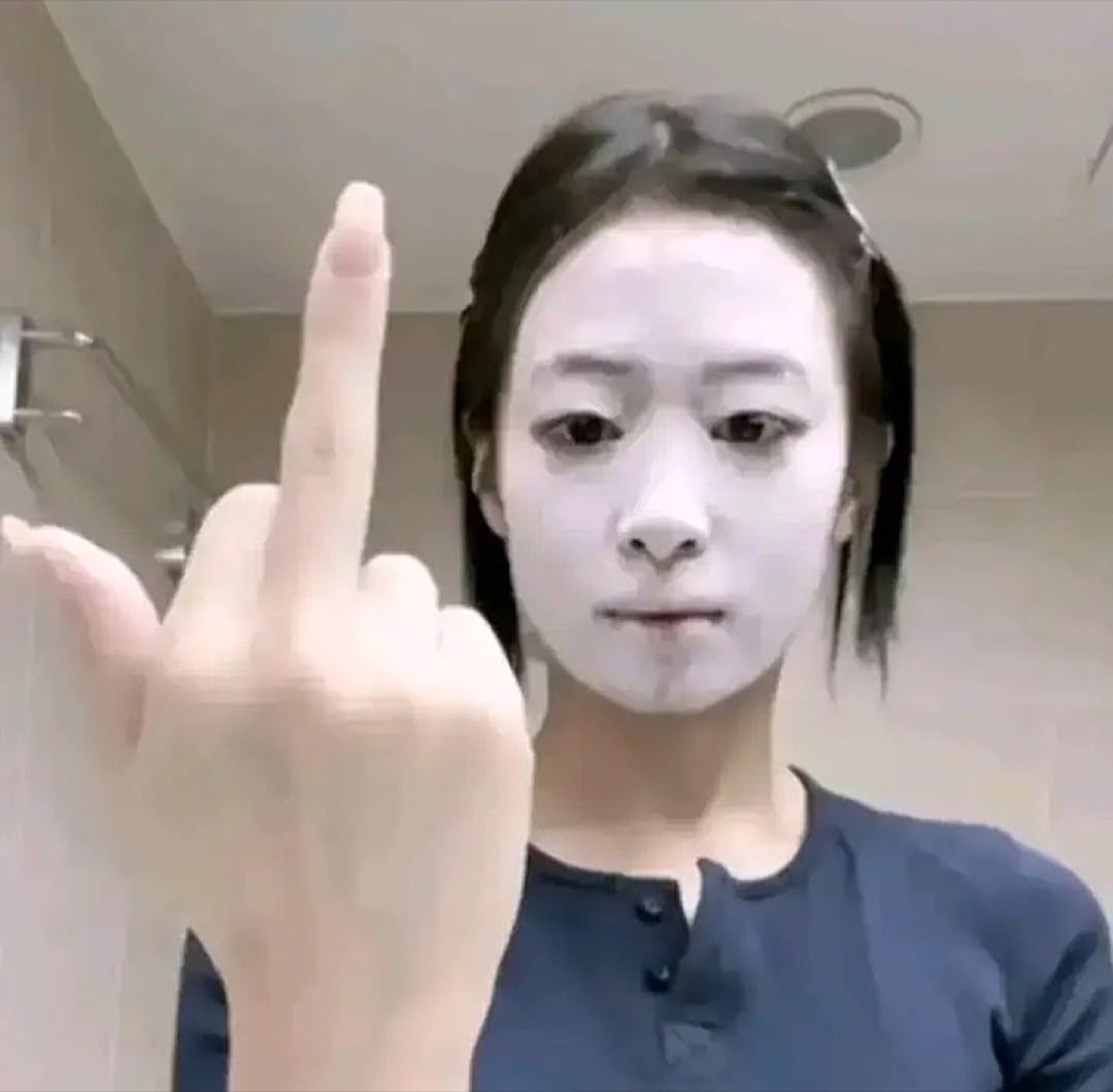 Woman in a white face mask flipping off the camera with a deadpan stare