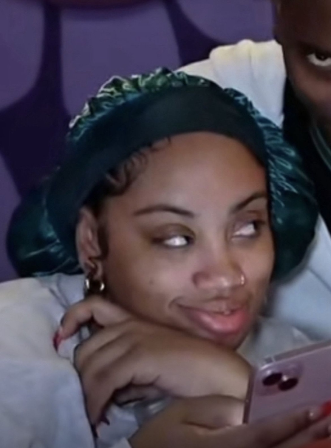 Woman in a satin bonnet resting on her arm shooting a sly sideways glance