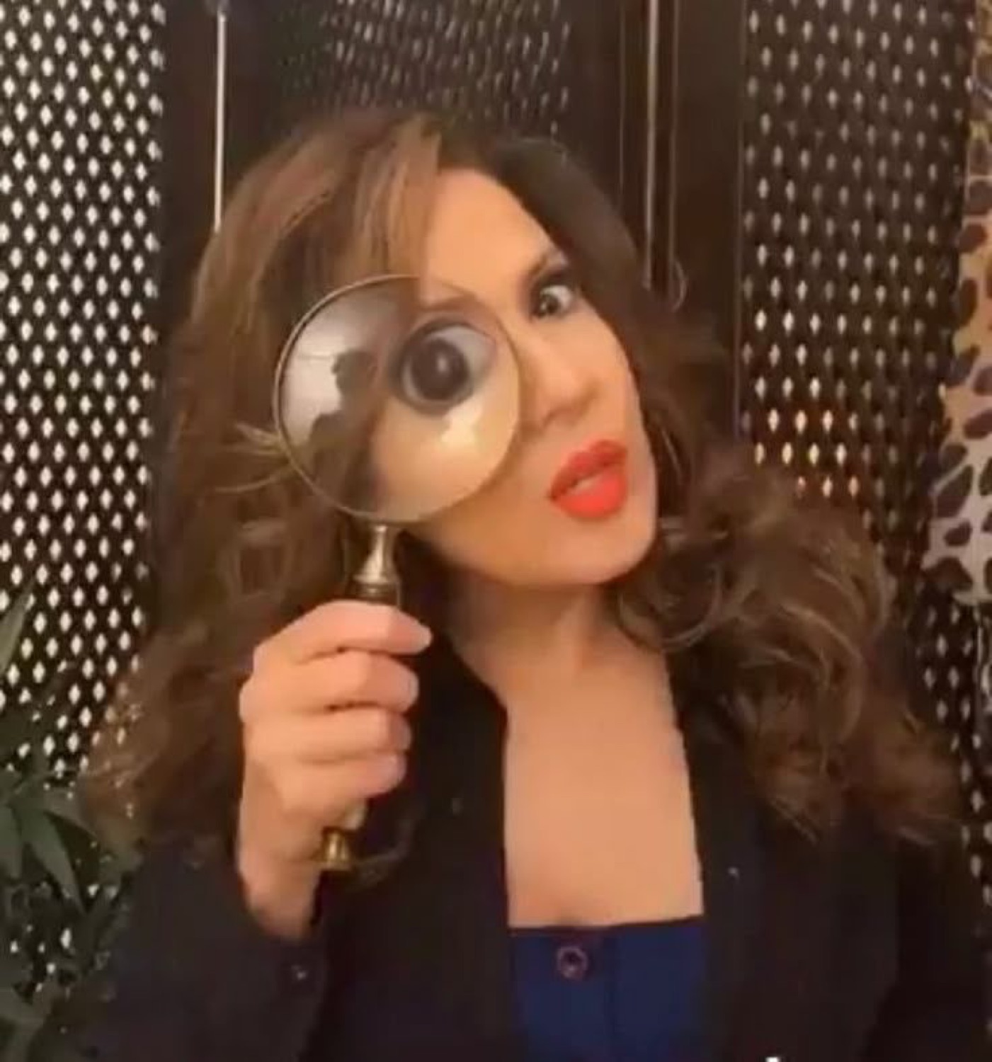 Woman holding a magnifying glass to one eye, inspecting you very closely