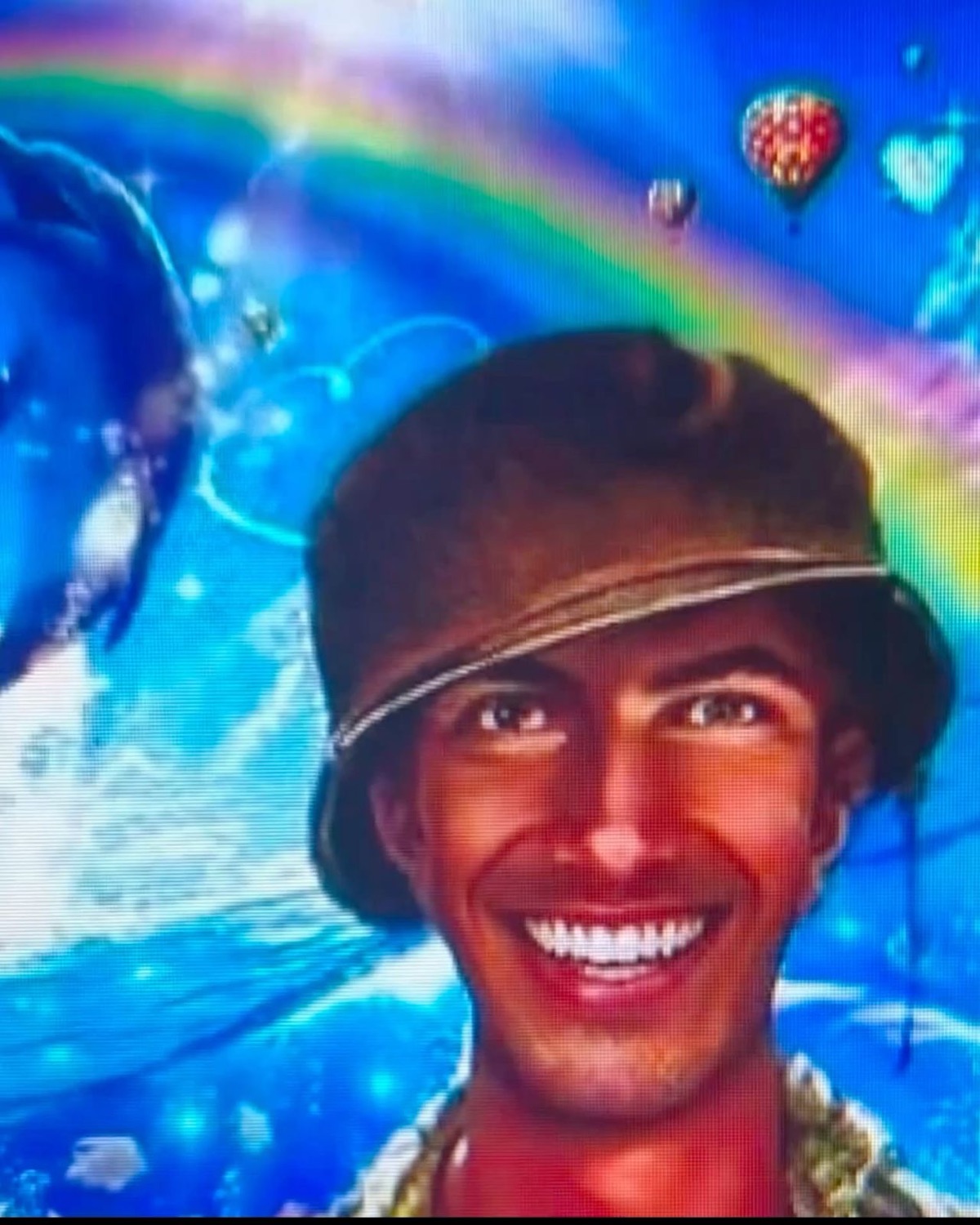 Man in a bucket hat beaming in front of an edited rainbow-and-dolphins backdrop