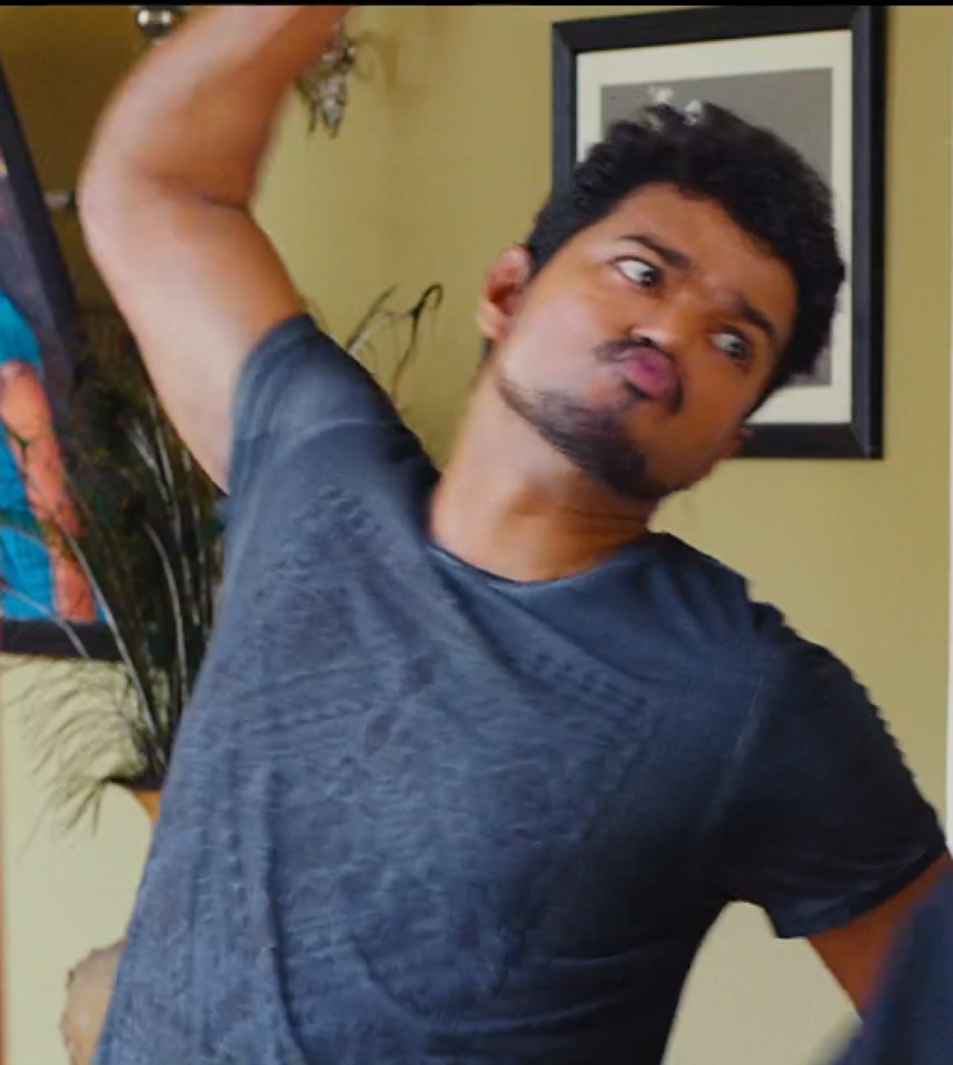 Vijay posing awkwardly with one arm over his head and pursed lips
