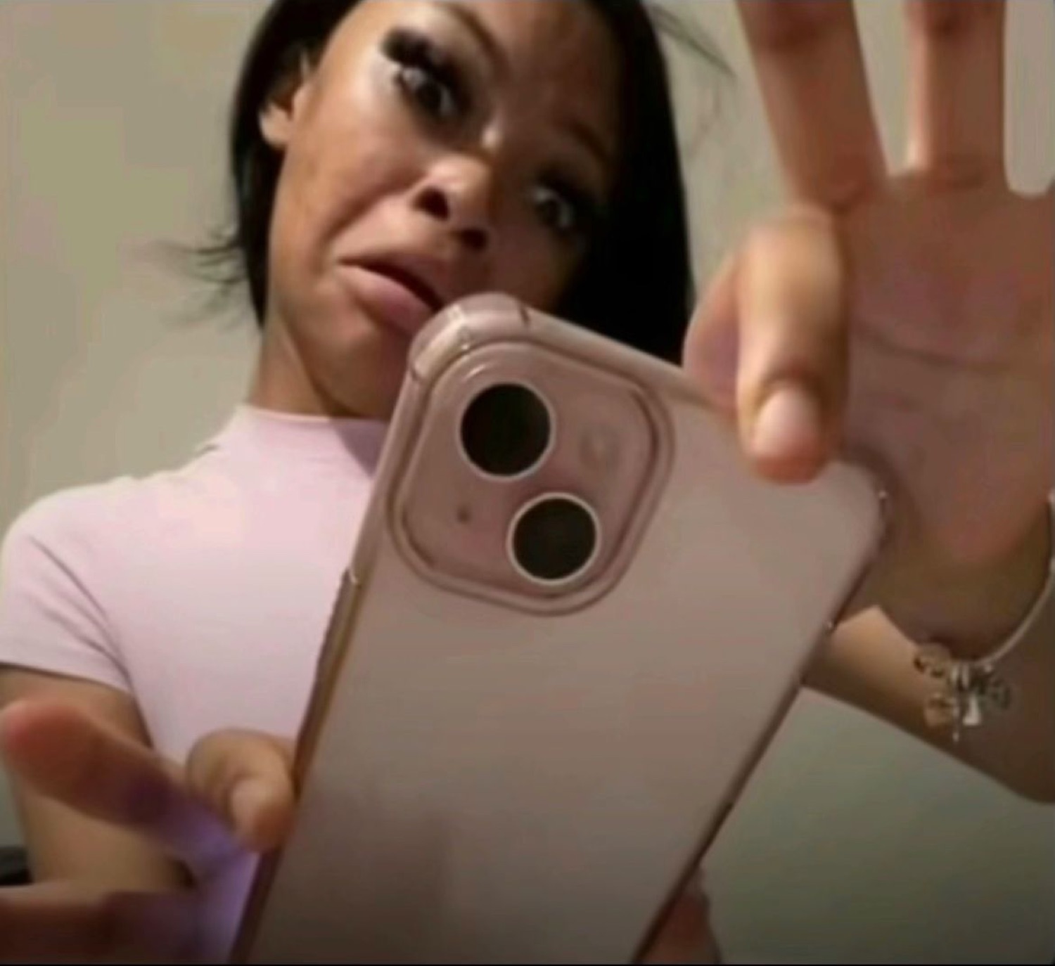Mirror selfie of a woman holding her phone up with a tired, over-it expression