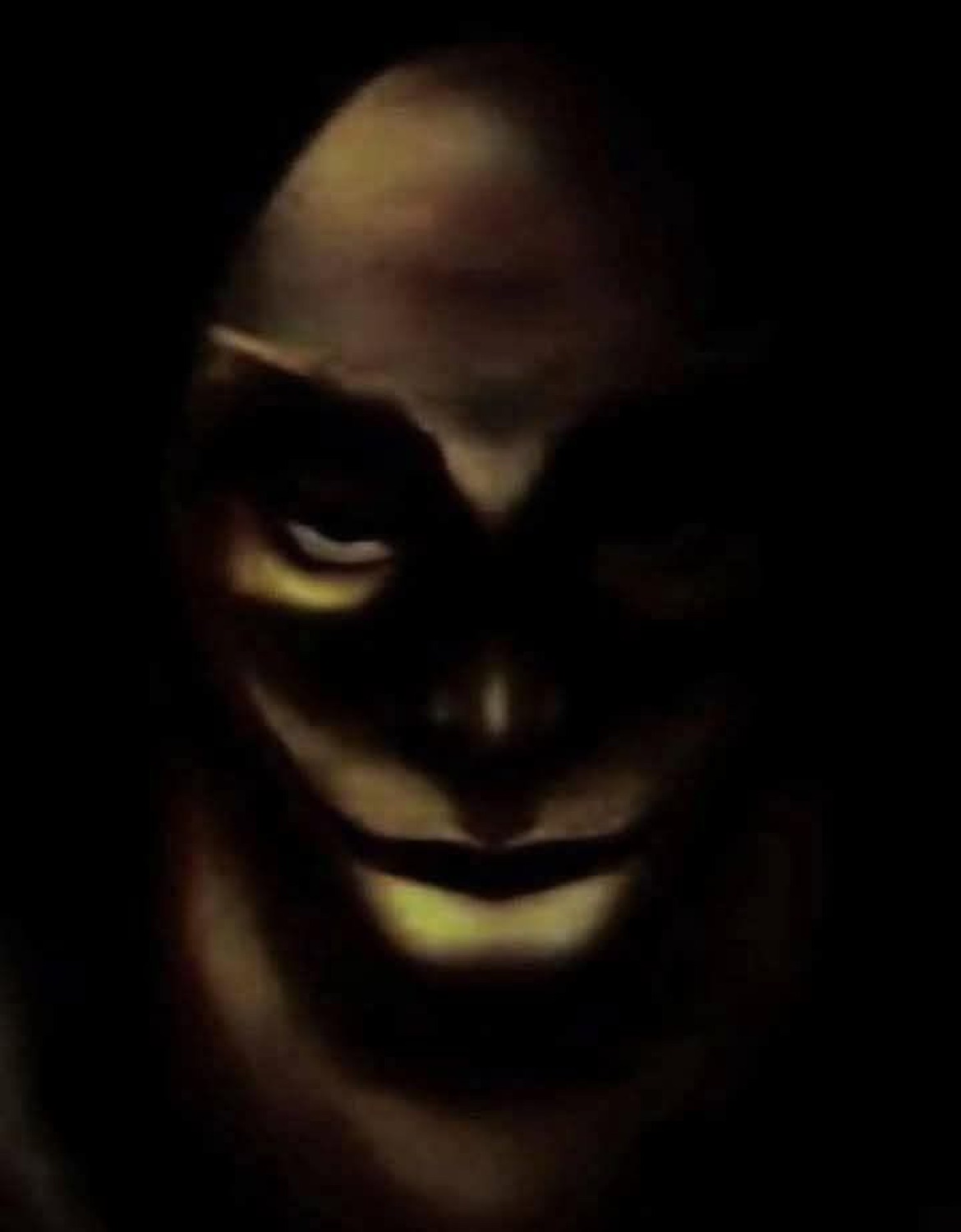 Shadowy dimly-lit face with a wide, unsettling grin lurking in the dark