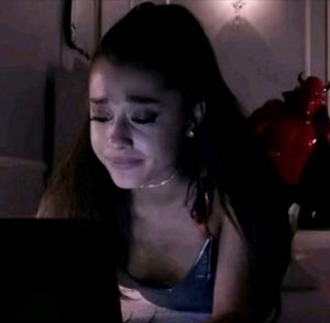 Ariana Grande crying at a laptop in the dark, lit only by the screen glow