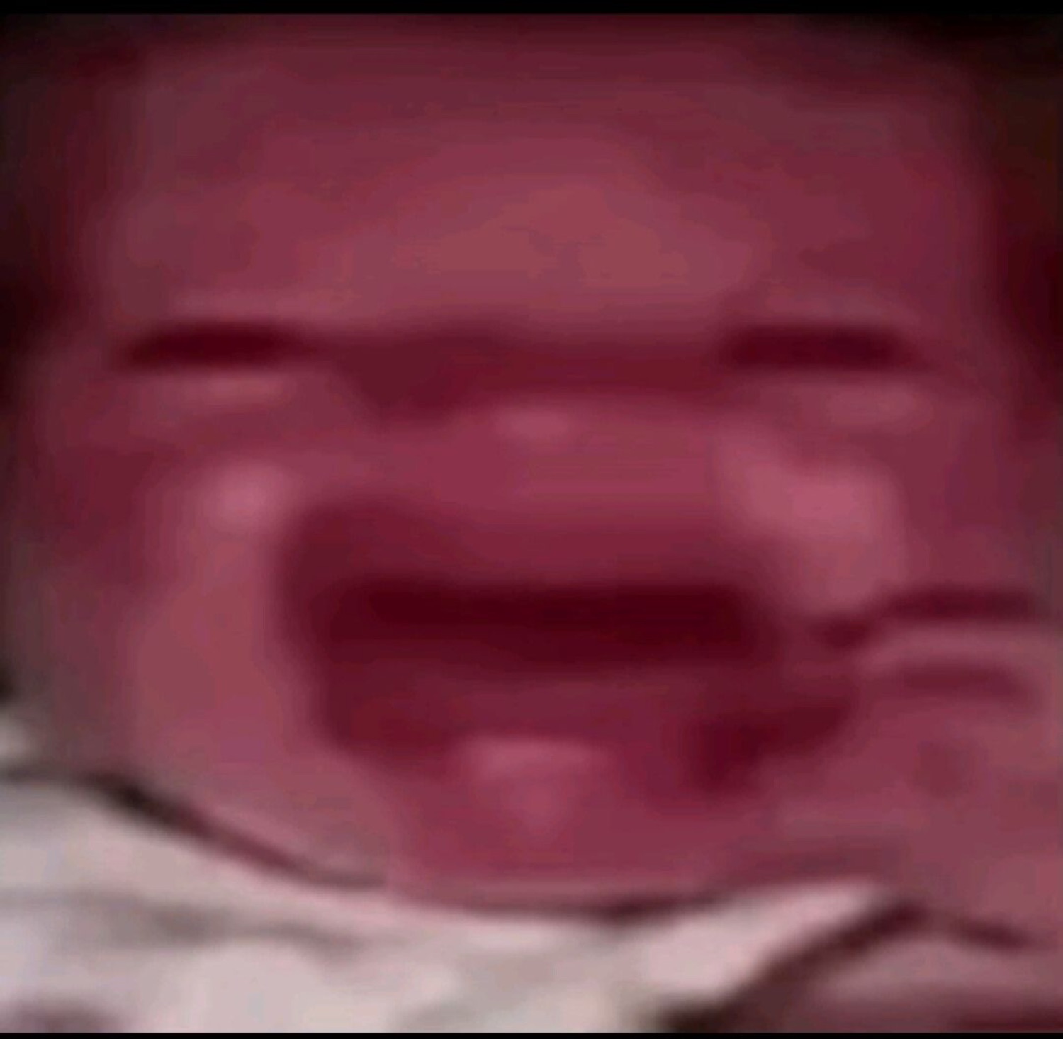 Extremely blurry red-tinted close-up of a face scrunched up mid-cry