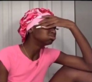 Woman in a pink bonnet pressing her hand to her forehead in total exasperation