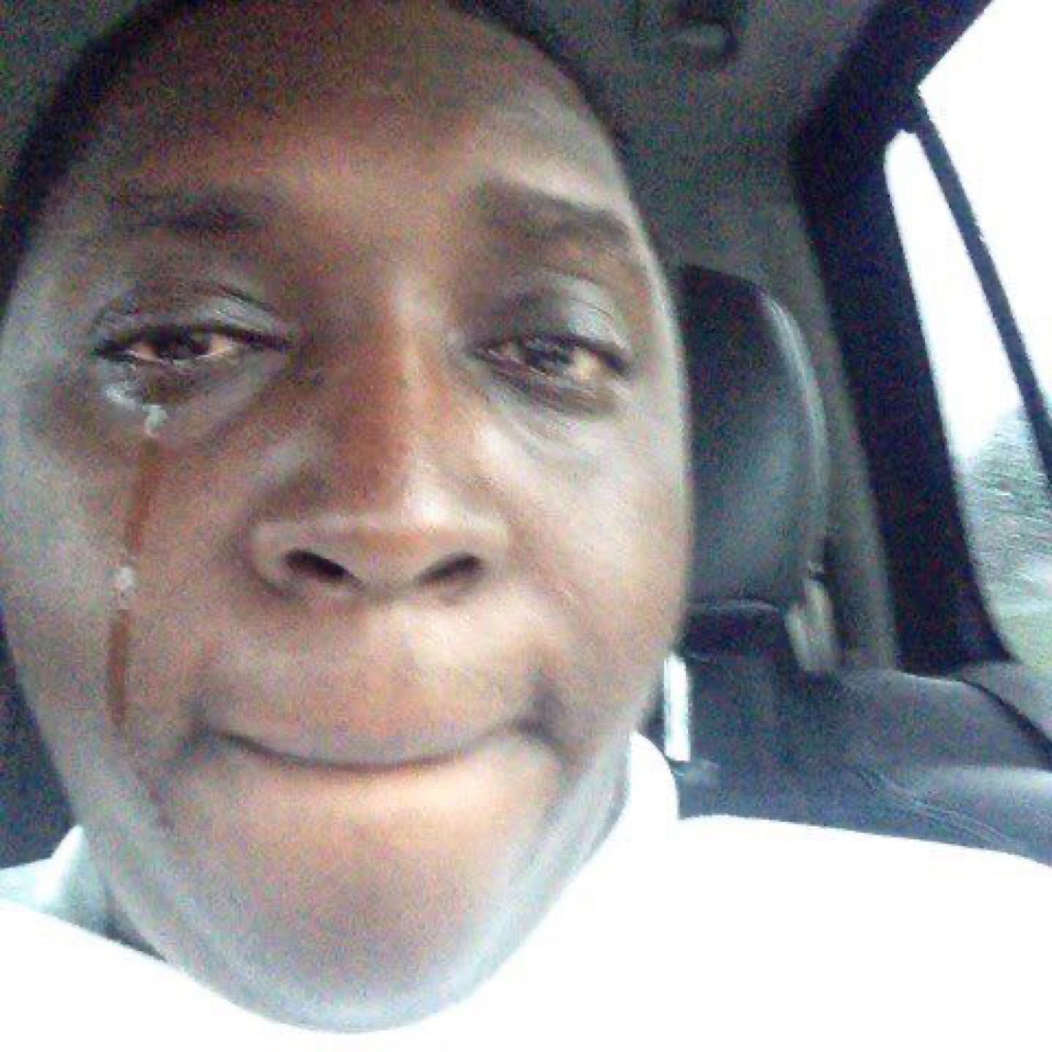 Man in a car with a single tear streaming down, trying to hold it together