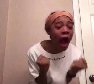 Woman in a headwrap with clenched fists and mouth wide open, screaming with excitement