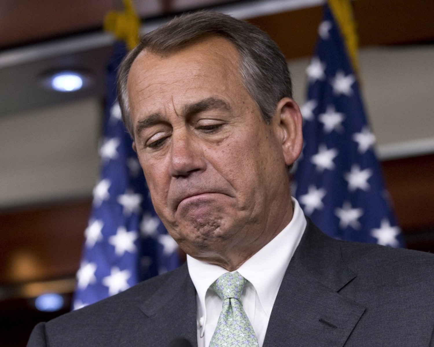 Politician at a podium closing his eyes with a deeply disappointed frown