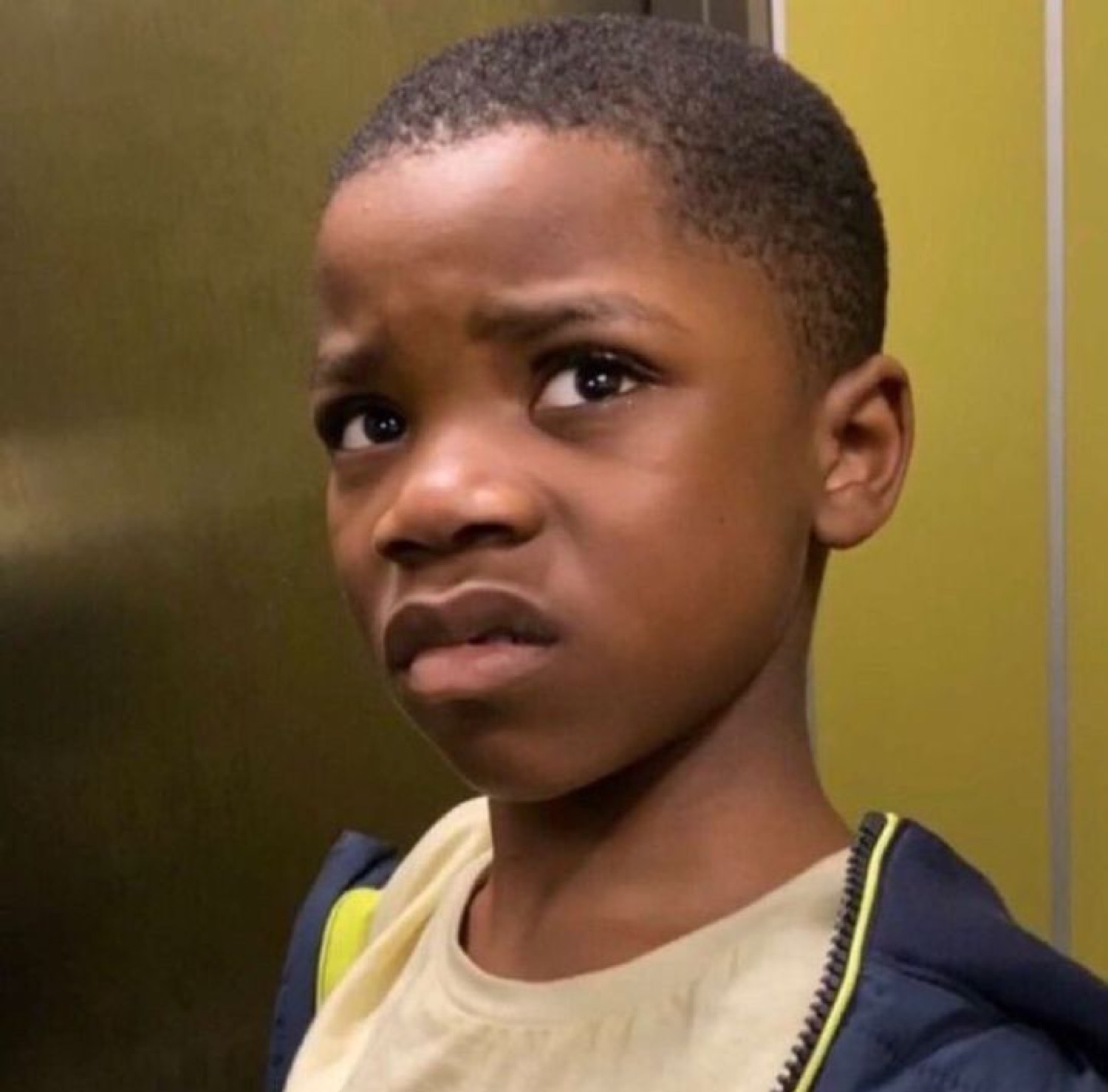 Young boy with furrowed brows giving a skeptical, displeased stare